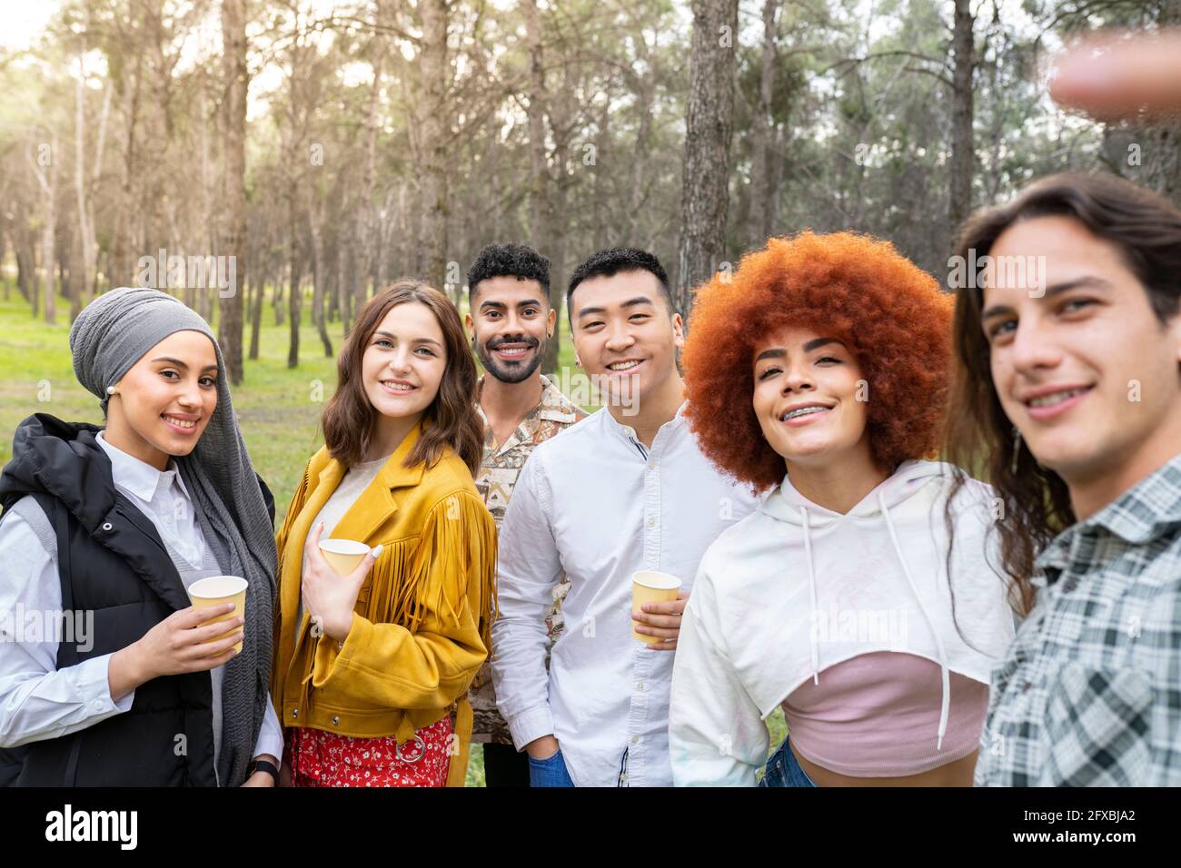 Multi-ethnic male and female friends taking selfie while enjoying at forest Stock Photo