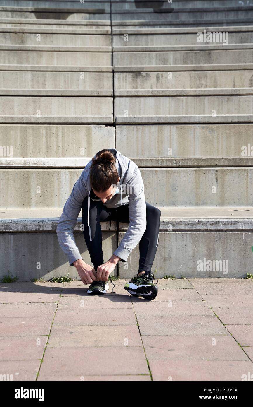 Man tying shoelace while sitting on steps Stock Photo