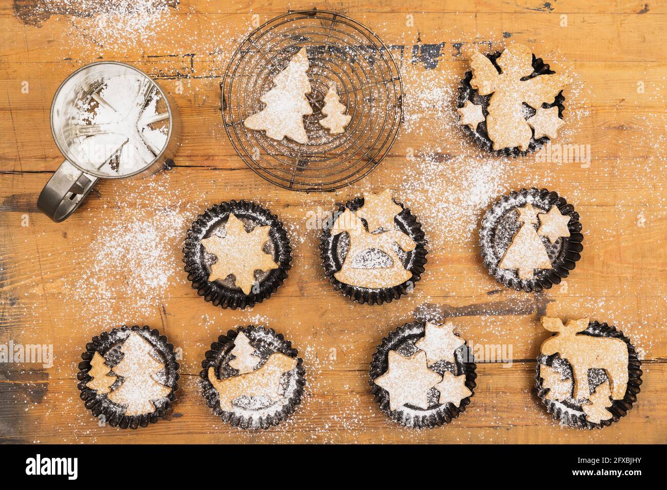 Powdered sugar shaker and fresh homemade Christmas cookies lying on wooden surface Stock Photo