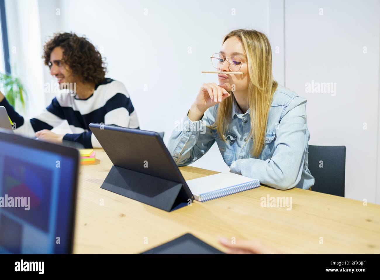 Thoughtful blond businesswoman with hand on chin working in office Stock Photo
