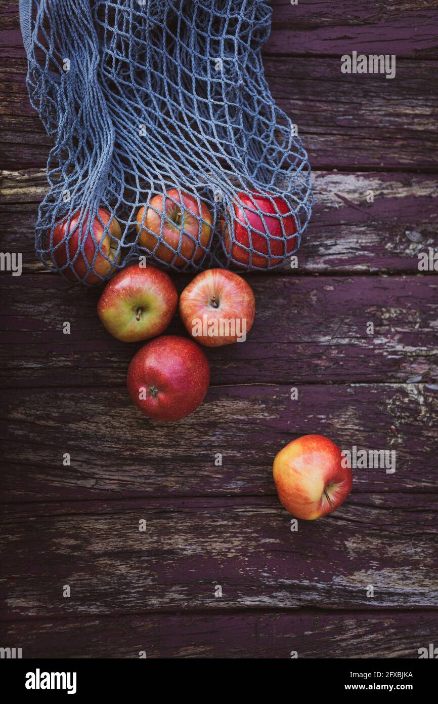 Apples with mesh bag on wooden table Stock Photo