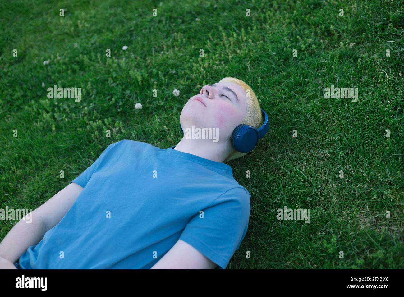 caucasian boy lying on the grass with headphones Stock Photo