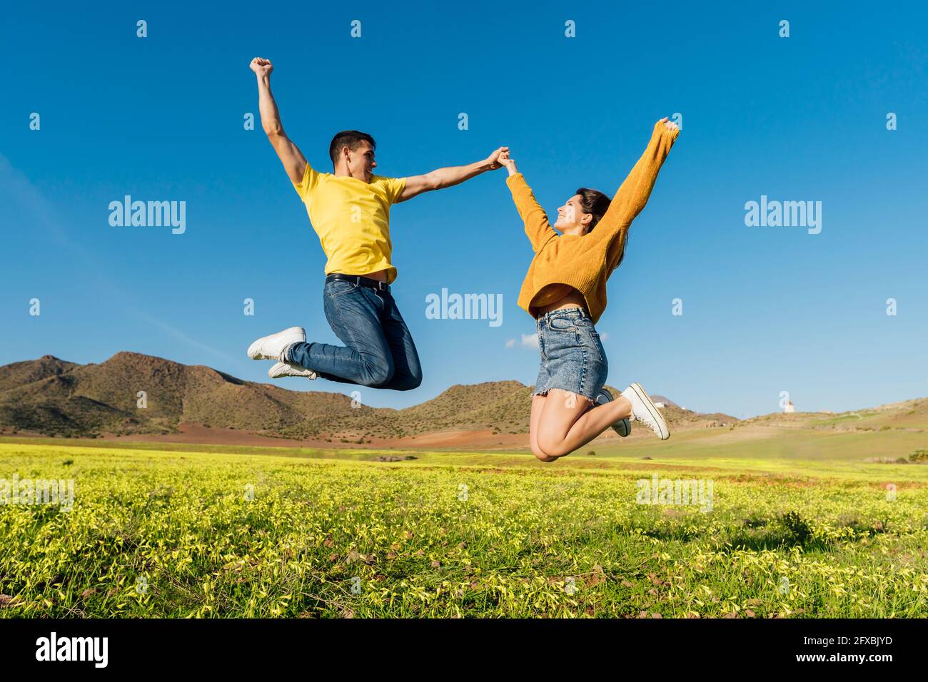 Young couple jumping with joy over grass Stock Photo