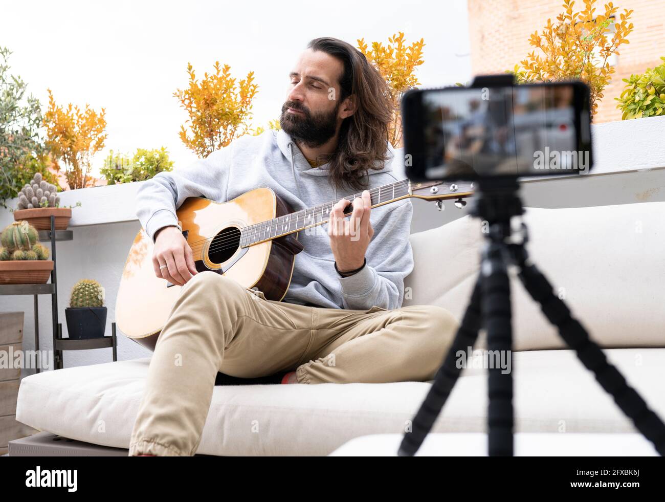 Male influencer vlogging while playing guitar on balcony Stock Photo - Alamy