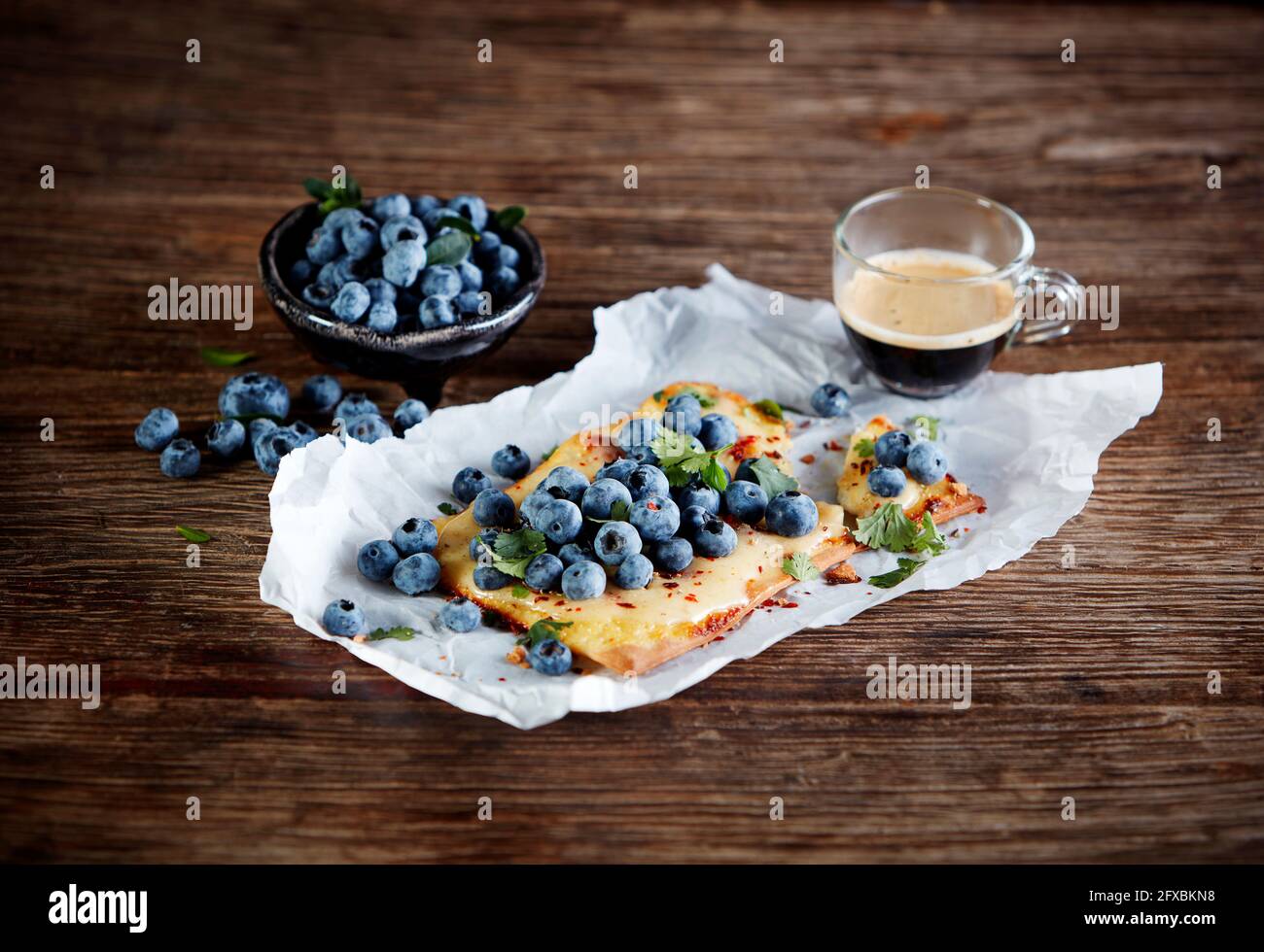 Studio shot of cup of coffee and lemon curd tart with blueberries and cilantro Stock Photo