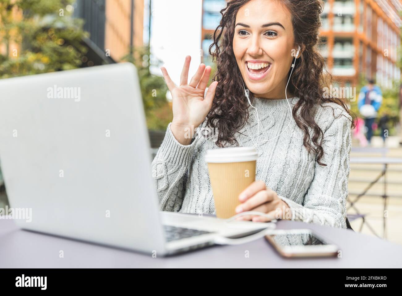 Smiling female professional waving during video call through laptop at cafe Stock Photo