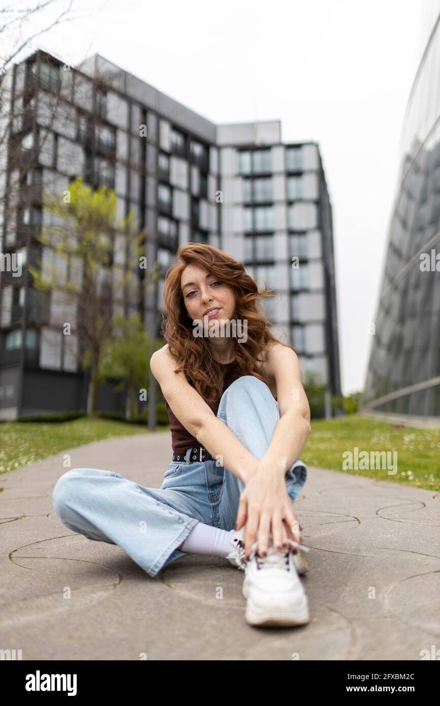 Woman sitting on footpath Stock Photo