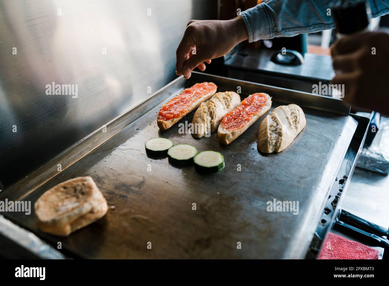 Waiter seasoning veggies while preparing sandwich in a restaurant Stock Photo