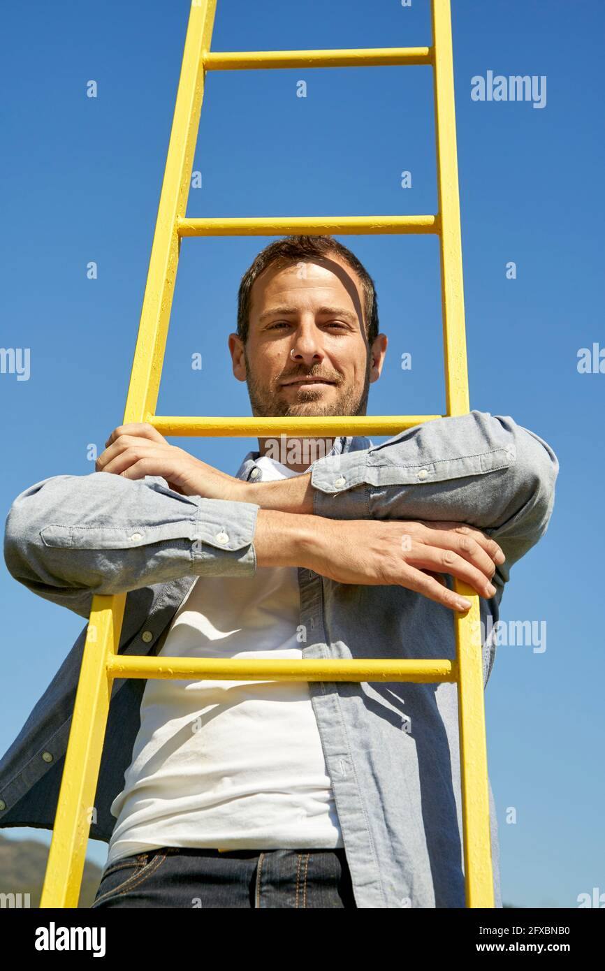 Man with arm around ladder Stock Photo