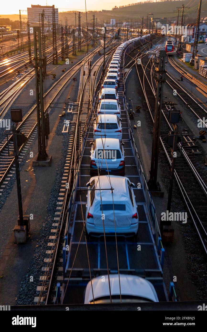 Germany, Bavaria, Wurzburg, Row od cars transported along city railroad tracks at sunset Stock Photo