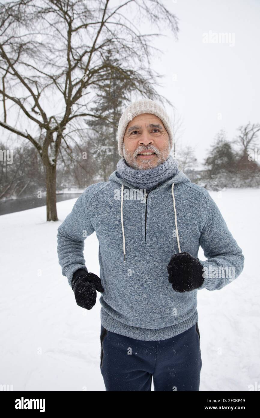 Man wearing knit hat and hooded shirt running at park Stock Photo