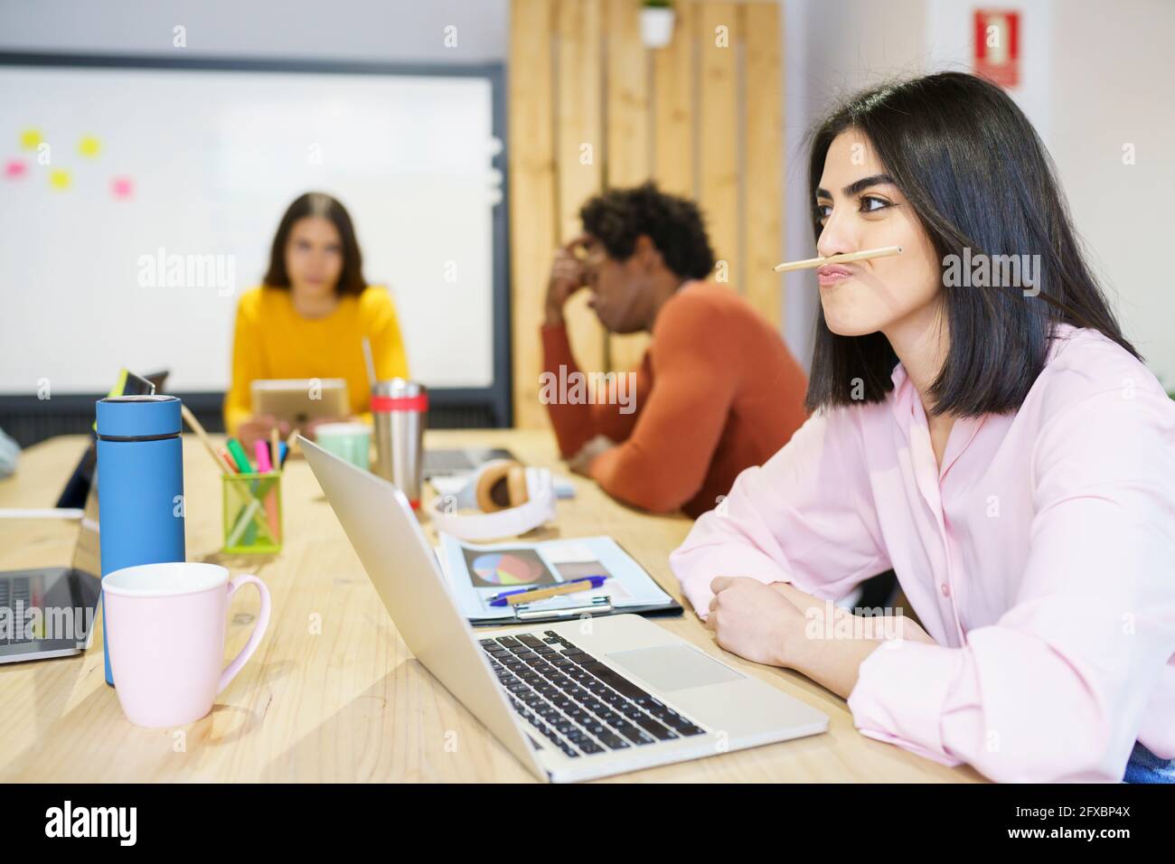 Creative businesswoman having fun with pen in office Stock Photo