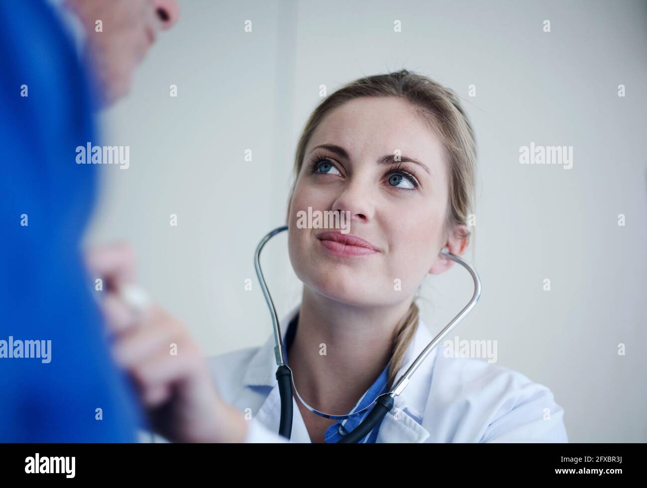 Female doctor checking senior patient with stethoscope in hospital ...