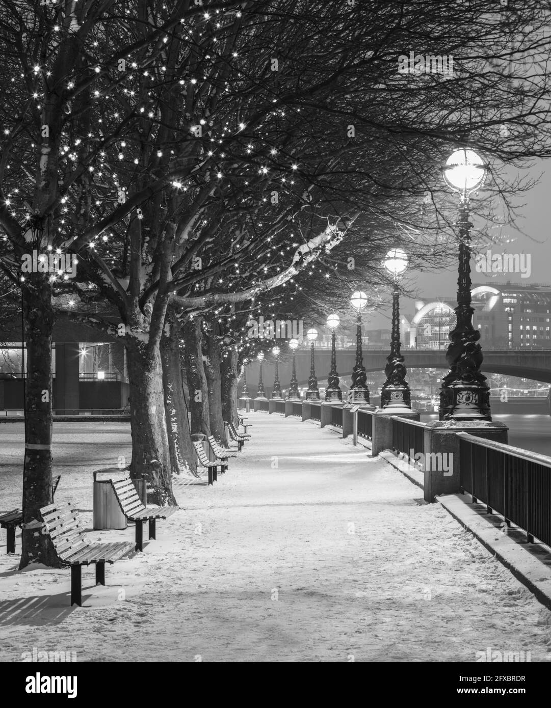 UK, England, London, Row of street lights illuminating empty snow-covered promenade Stock Photo