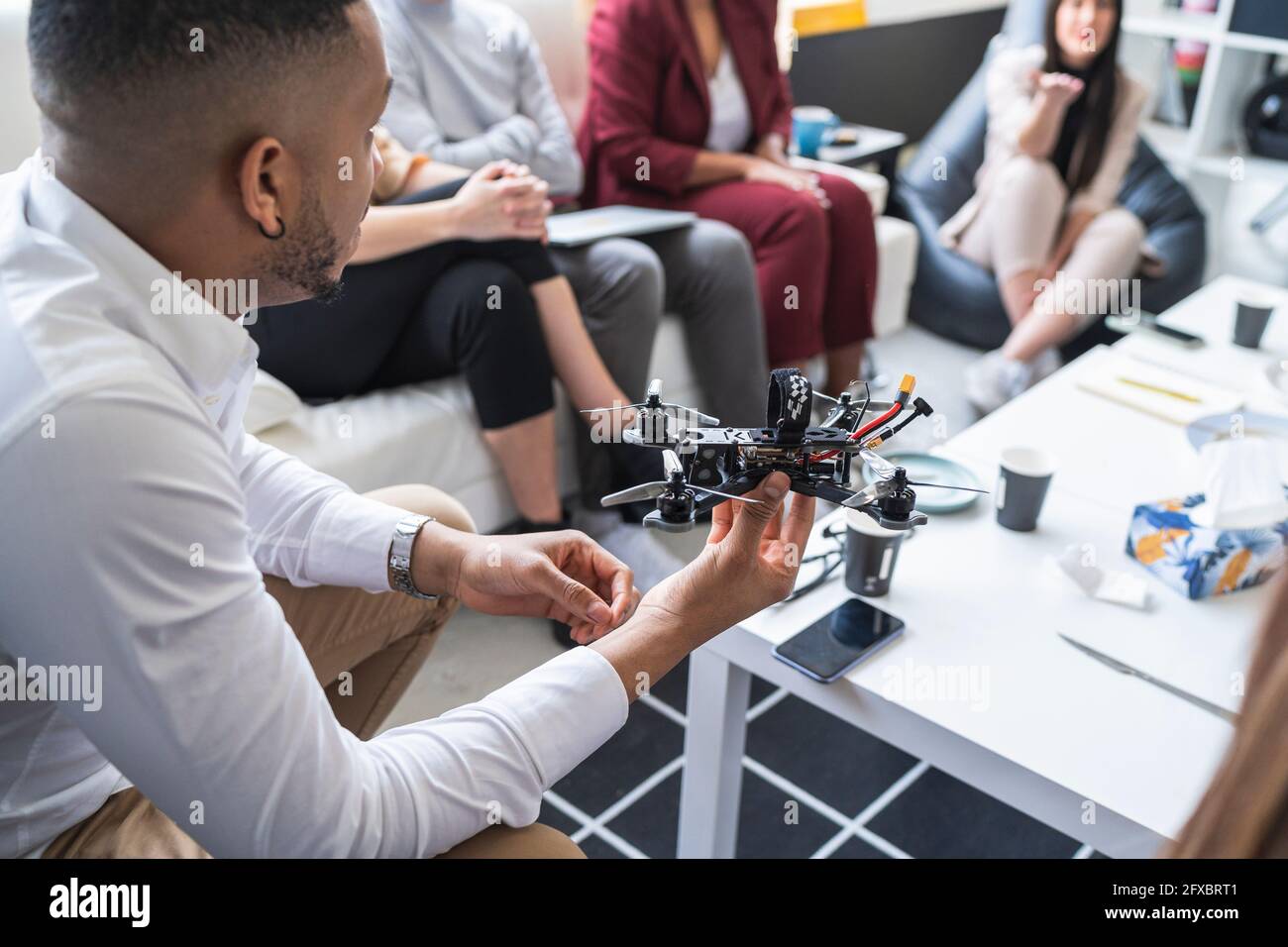 African male engineer discussing over drone with colleagues during ...