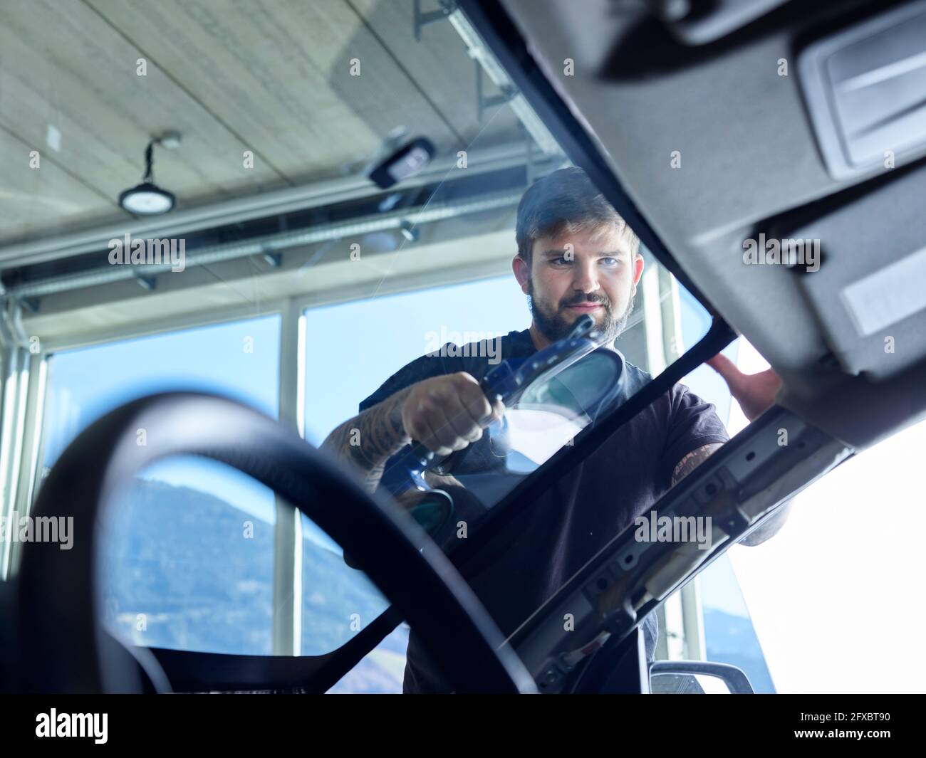 Repairman cleaning windshield of car at garage Stock Photo