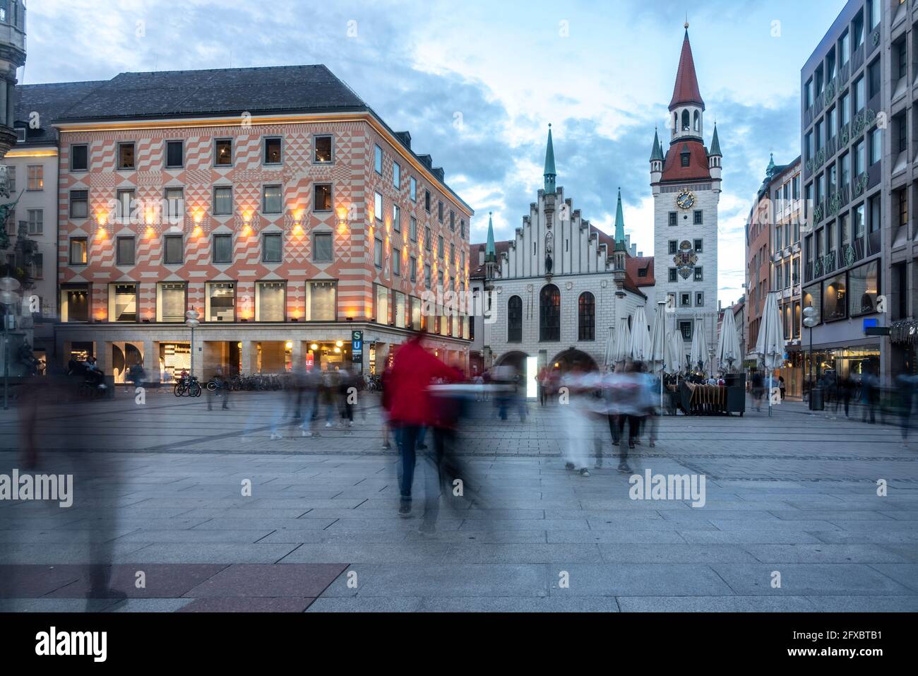 Incidental people walking on footpath during dusk at Marienplatz with Old Town Hall of Munich, Bavaria, Germany Stock Photo