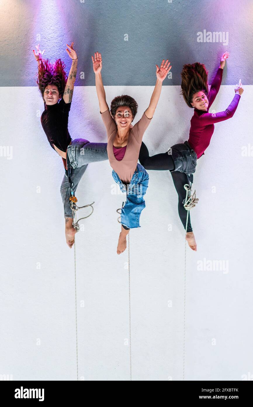Female dancers doing acrobatic activity while hanging on rope in dance studio Stock Photo