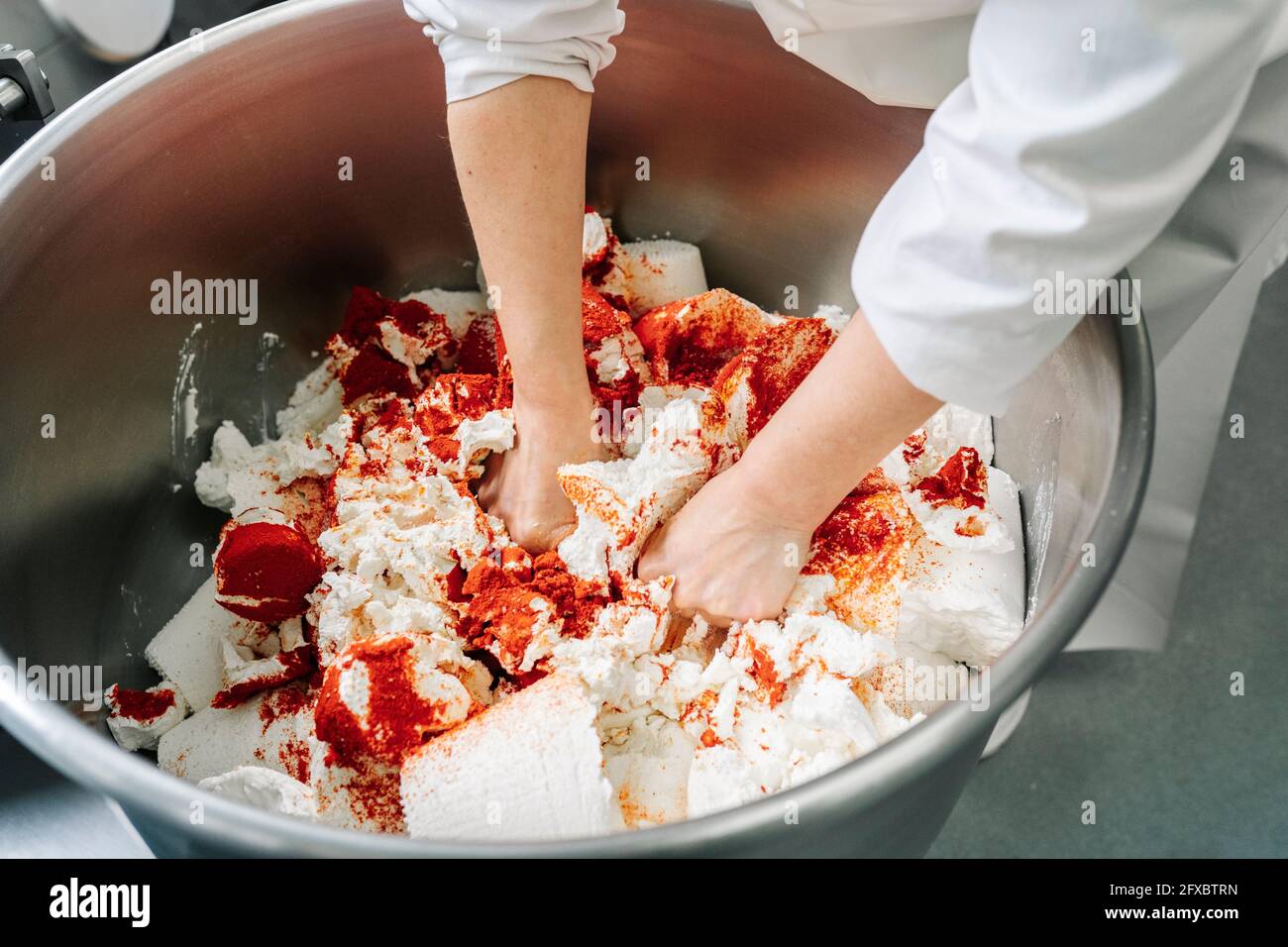 Skilled chef kneading cheese and ingredients in machinery at factory Stock Photo