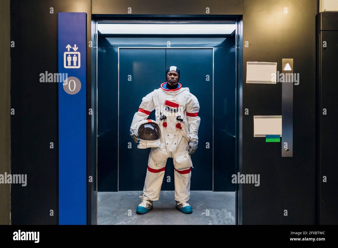Male astronaut with space helmet standing in elevator Stock Photo