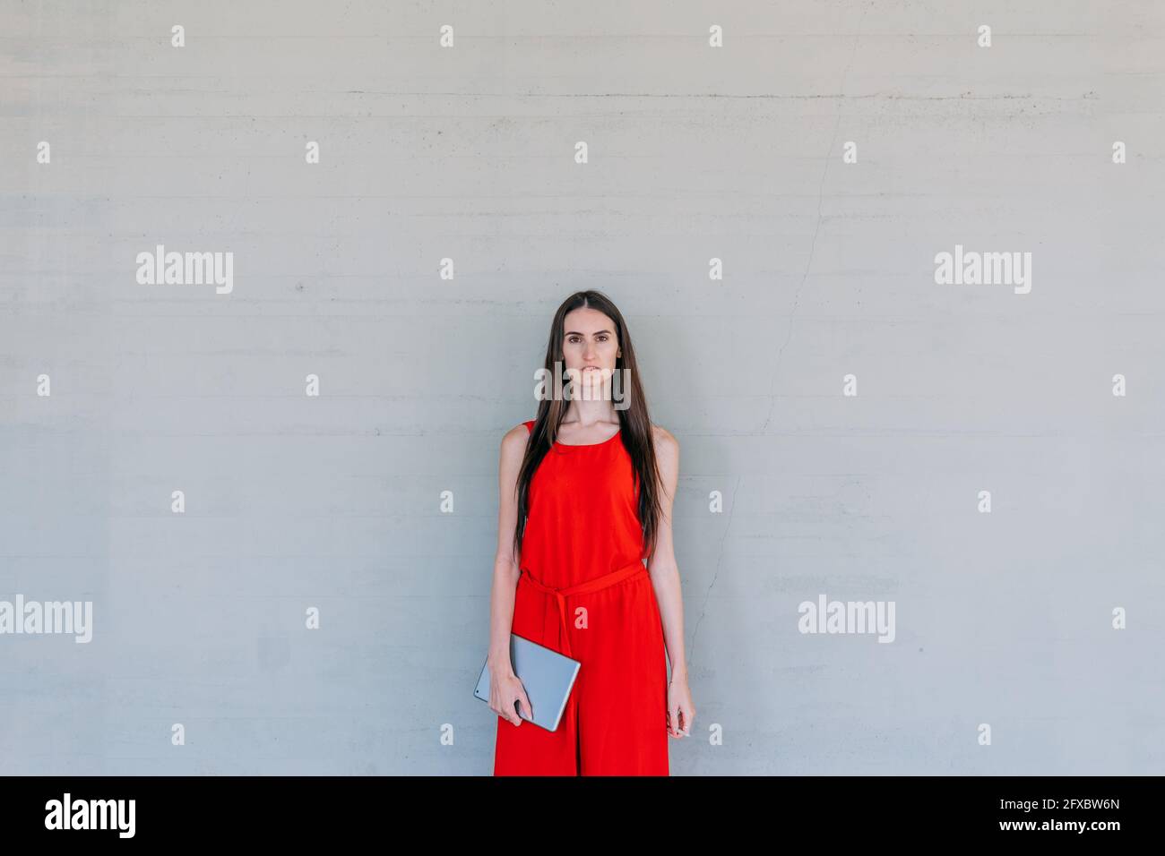 Young business woman in red dress, holding a tablet and looking at the camera. Business concept. Stock Photo