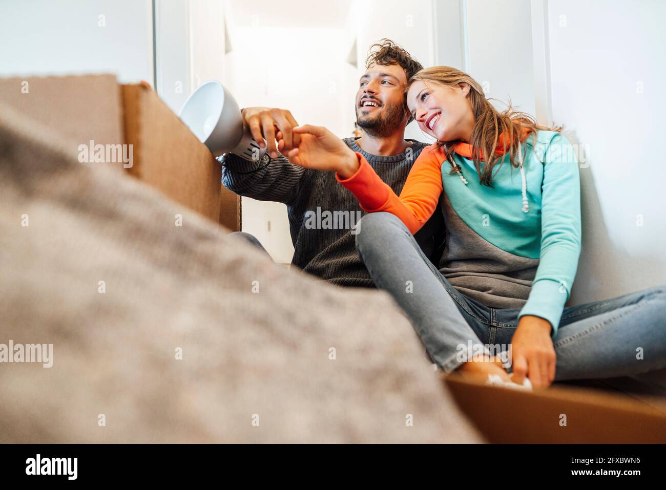 Happy young couple sitting together while looking away Stock Photo