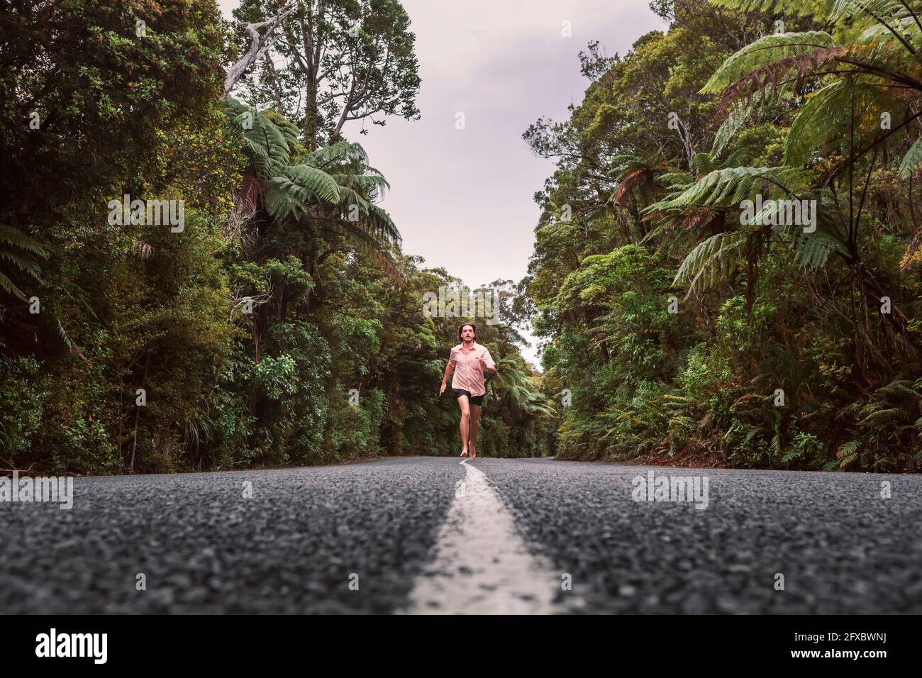 New Zealand, North Island, Northland, Young man running on road through