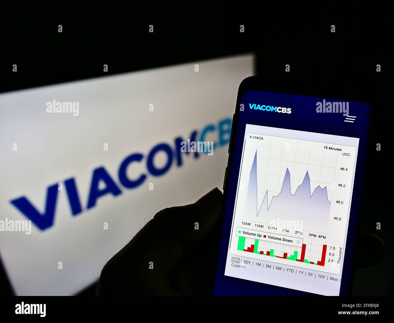 Person holding cellphone with webpage and chart of US mass media company ViacomCBS Inc. on screen in front of logo. Focus on center of phone display. Stock Photo