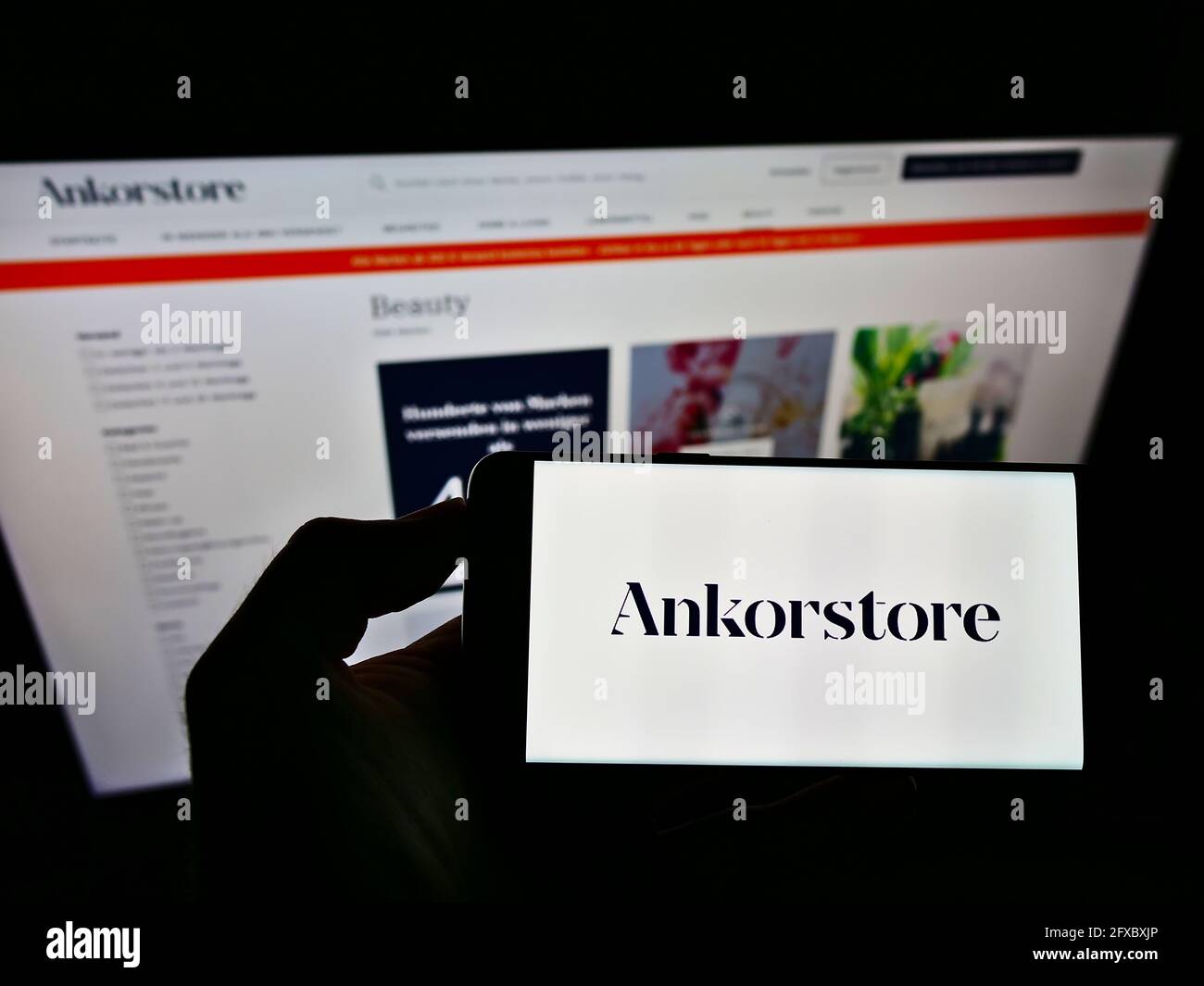 Person holding smartphone with logo of French B2B marketplace company Ankorstore SAS on screen in front of website. Focus on phone display. Stock Photo