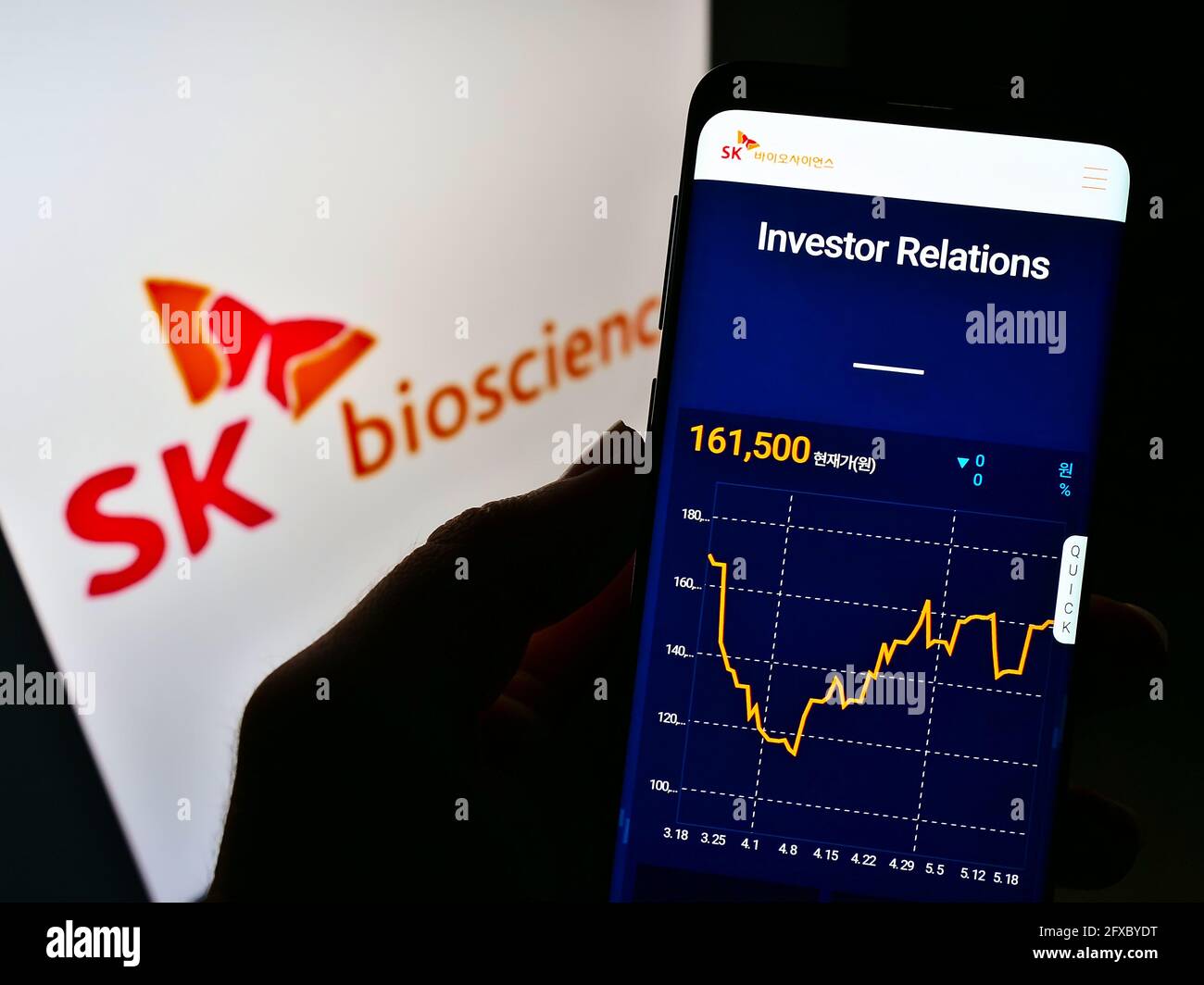 Person holding cellphone with webpage of South Korean biological company SK Bioscience on screen with logo. Focus on center of phone display. Stock Photo