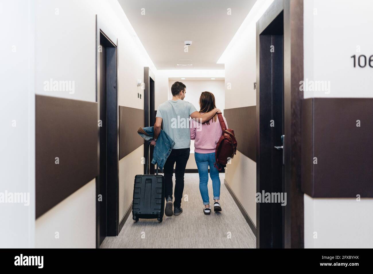 Couple walking with luggage at hotel corridor Stock Photo