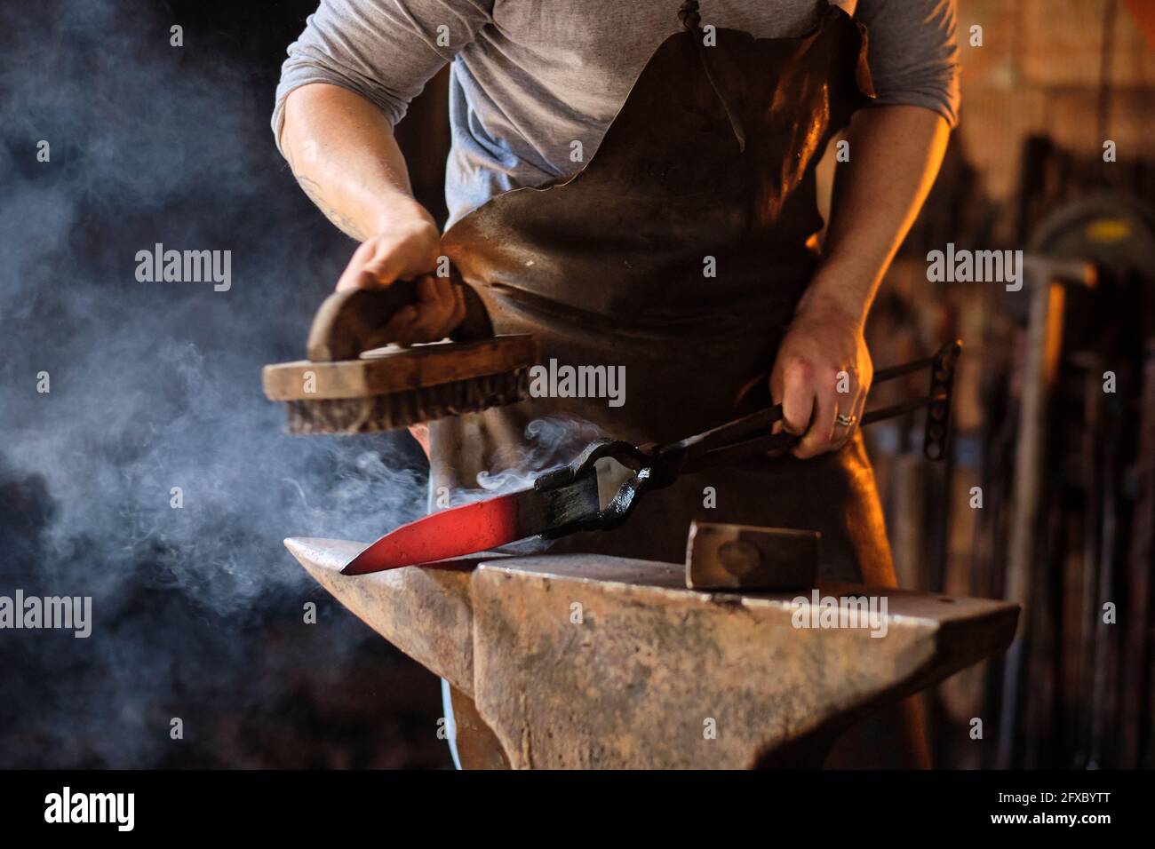 Young male craftsperson preparing metal knife on anvil at workshop Stock Photo