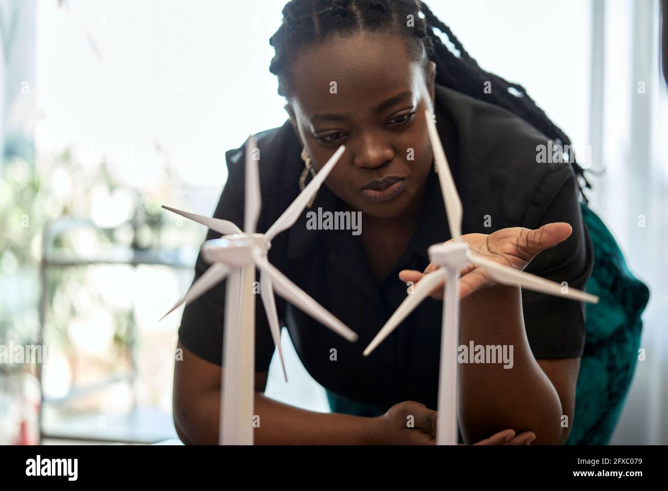 Woman examining wind turbine models at coworking office Stock Photo