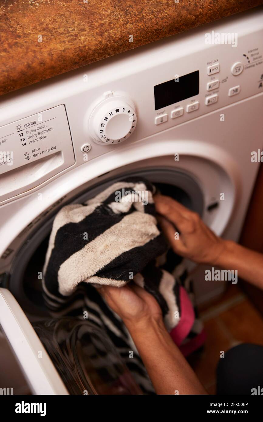 Mature woman loading clothes in washing machine at home Stock Photo