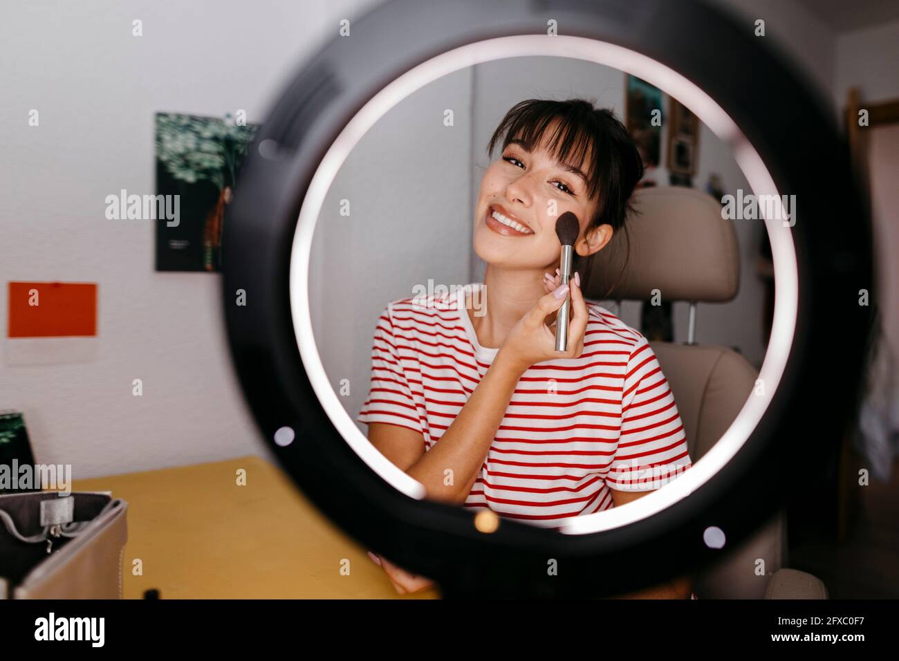 Beautiful female influencer applying blusher at studio Stock Photo