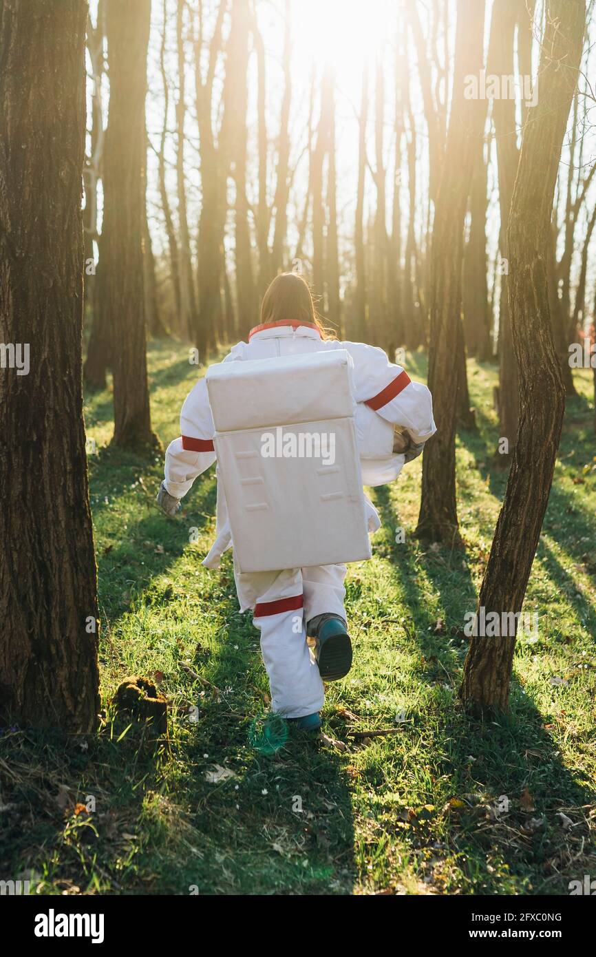Female astronaut wearing space suit running in forest Stock Photo