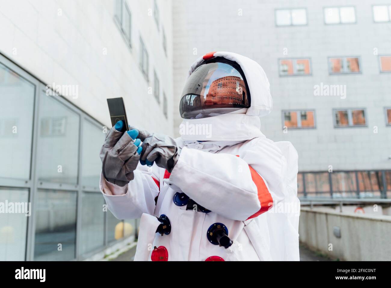 Female astronaut in space suit using smart phone outside building Stock ...