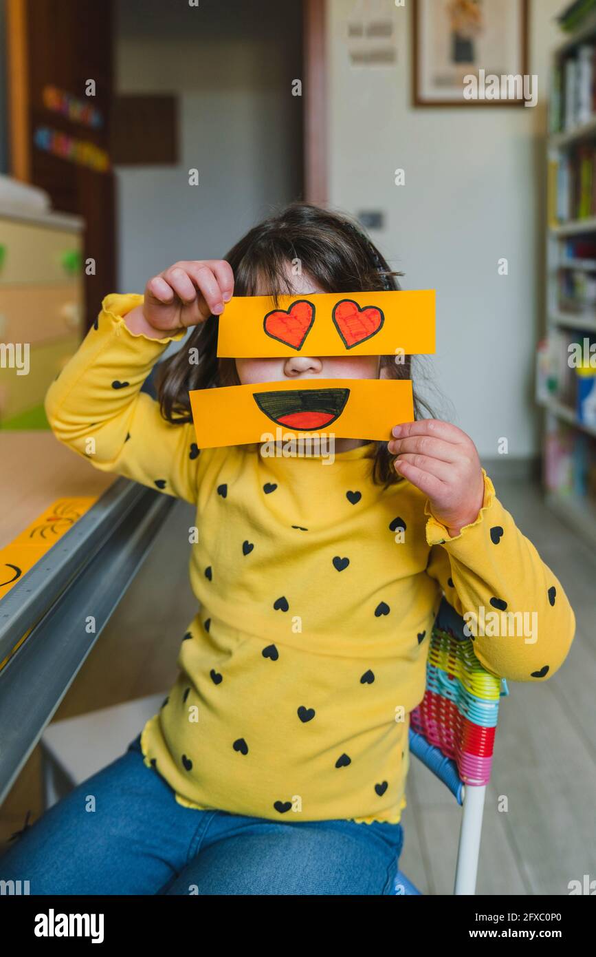 Girl sitting in playroom while playing with emoticons at home Stock Photo
