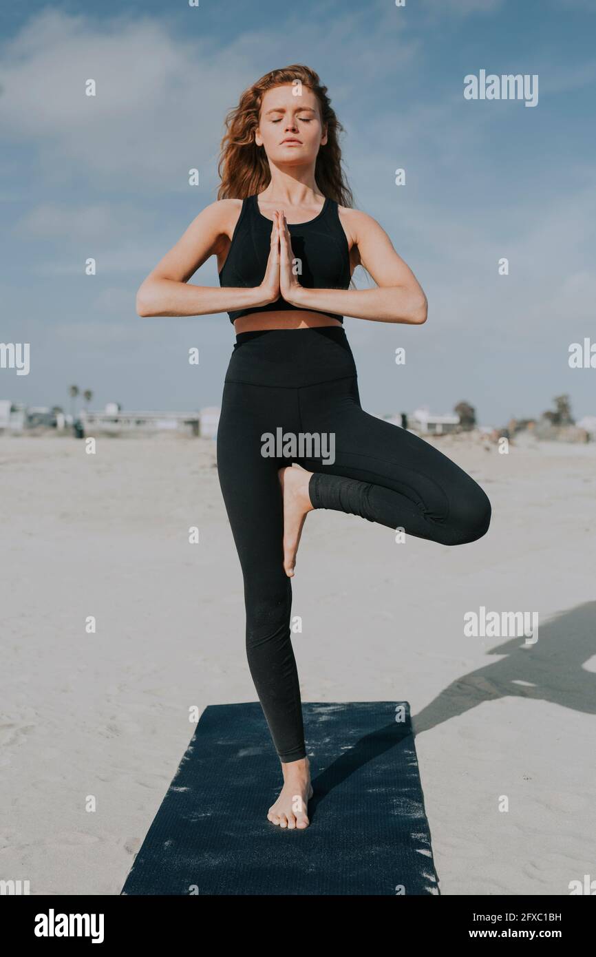Young woman practicing tree pose at beach during sunny day Stock Photo ...
