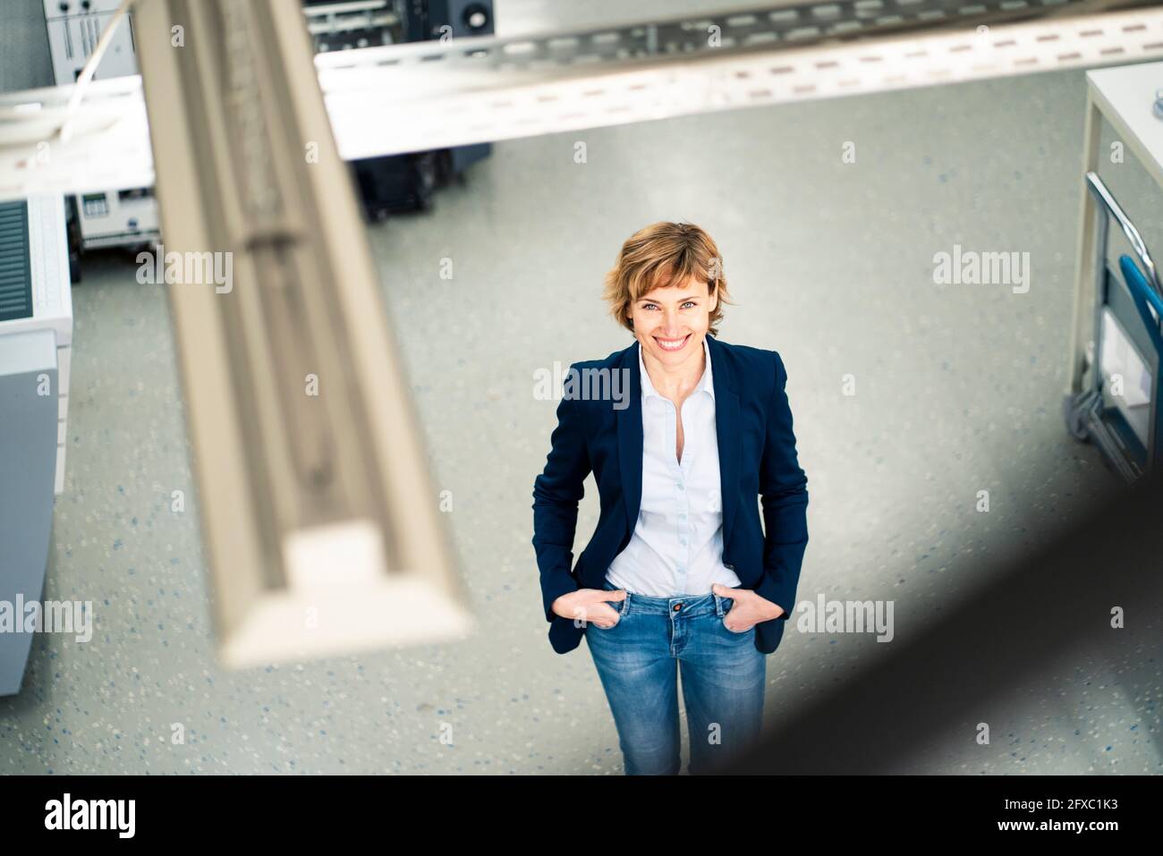 Smiling mature female owner standing with hands in pockets at printing industry Stock Photo