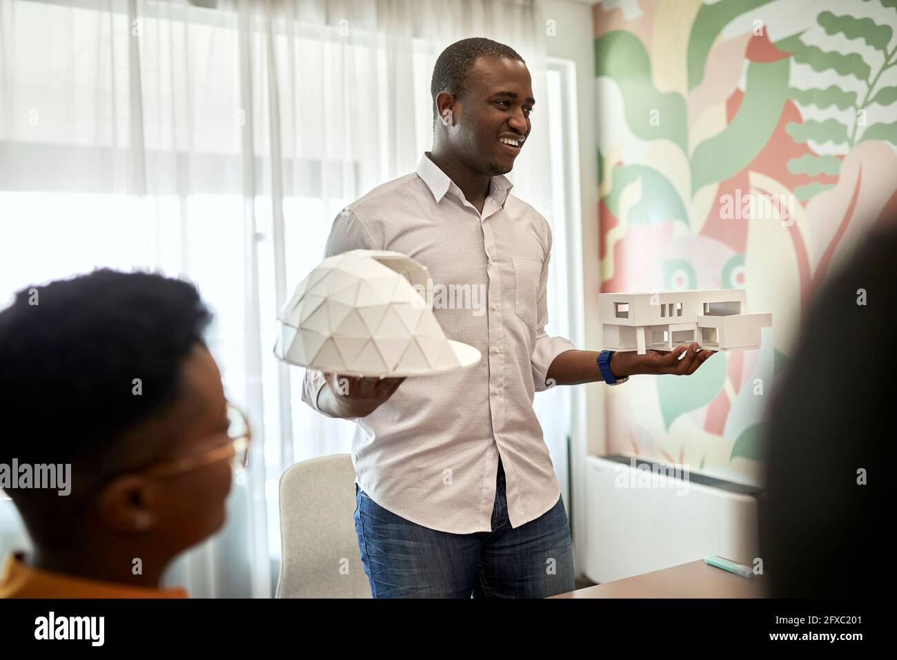 Smiling male architect explaining architectural models during meeting at coworking office Stock Photo