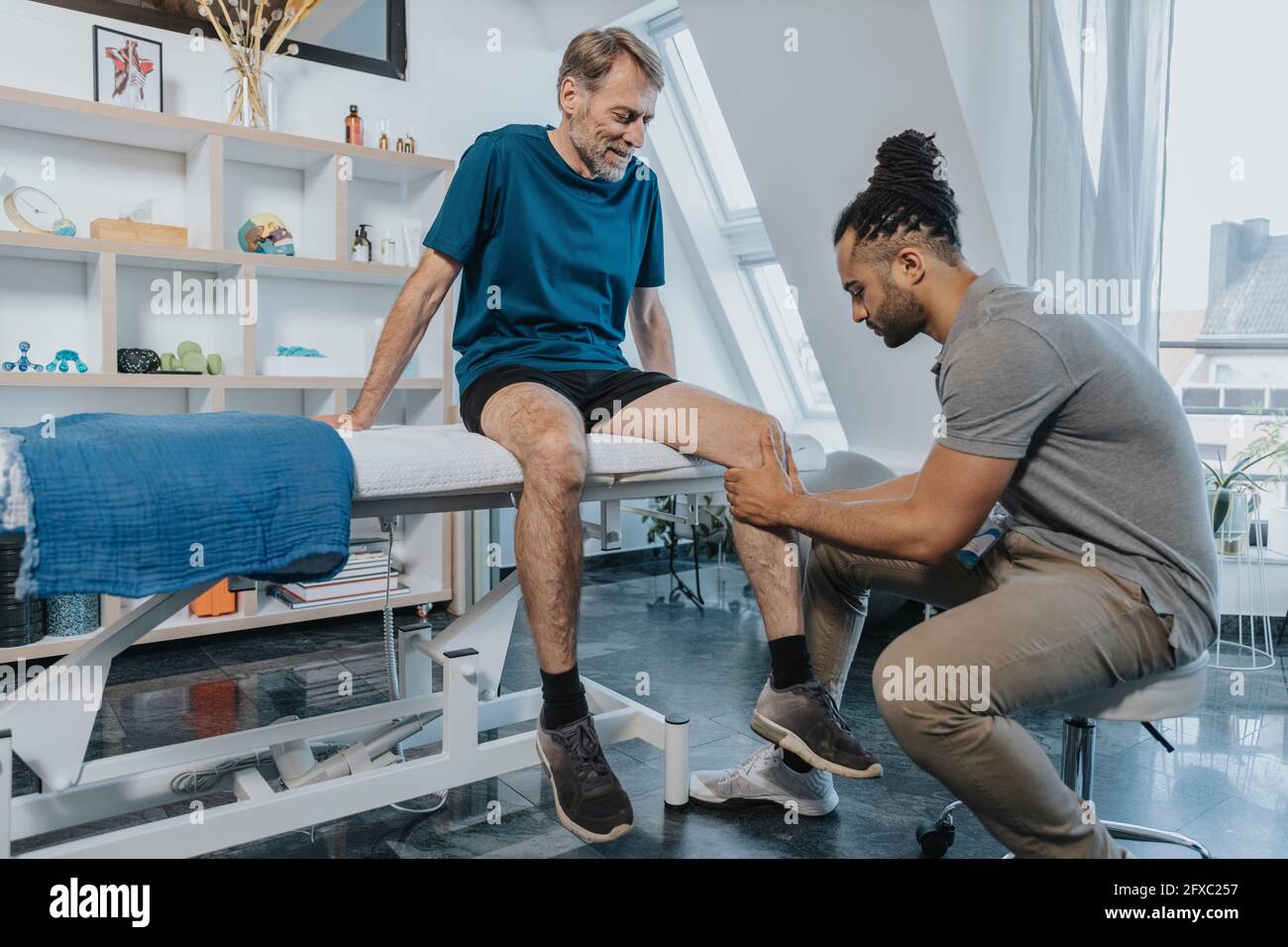 Male physiotherapist checking out knee of patient in practice Stock Photo