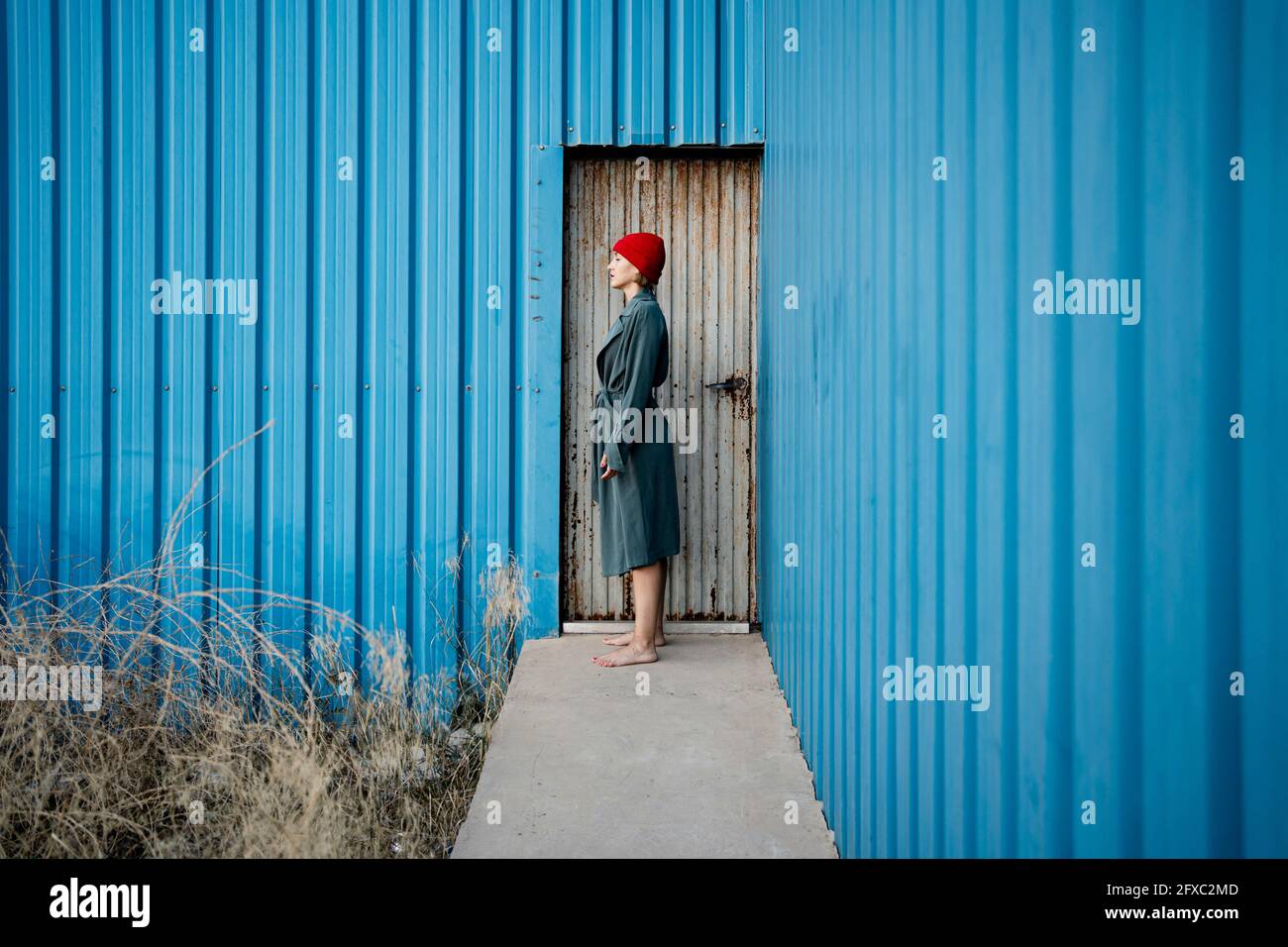 Woman wearing knit hat standing by corrugated iron door Stock Photo