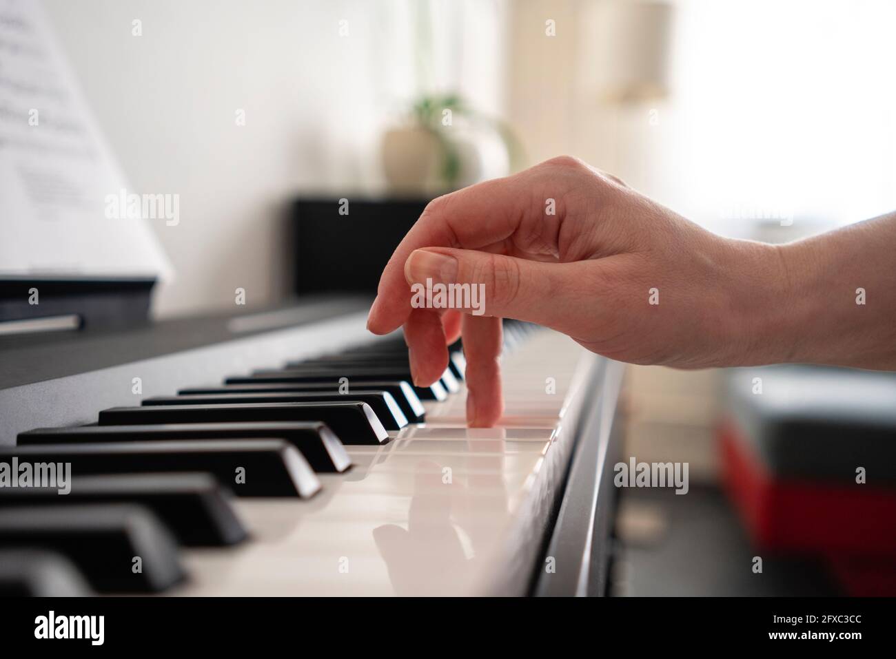 Mid adult woman playing piano at home Stock Photo