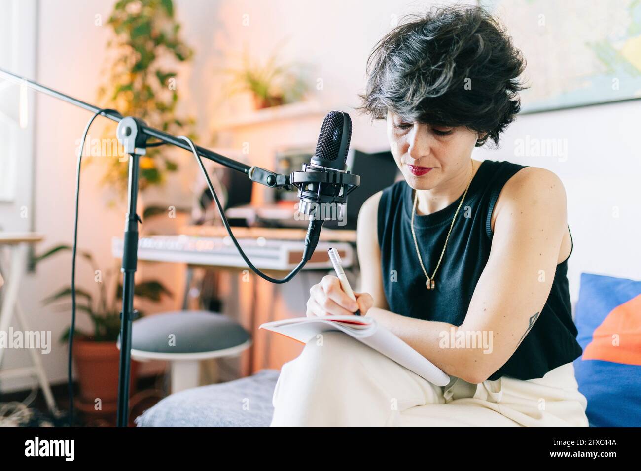 Female music composer writing in notepad while recording at studio Stock Photo
