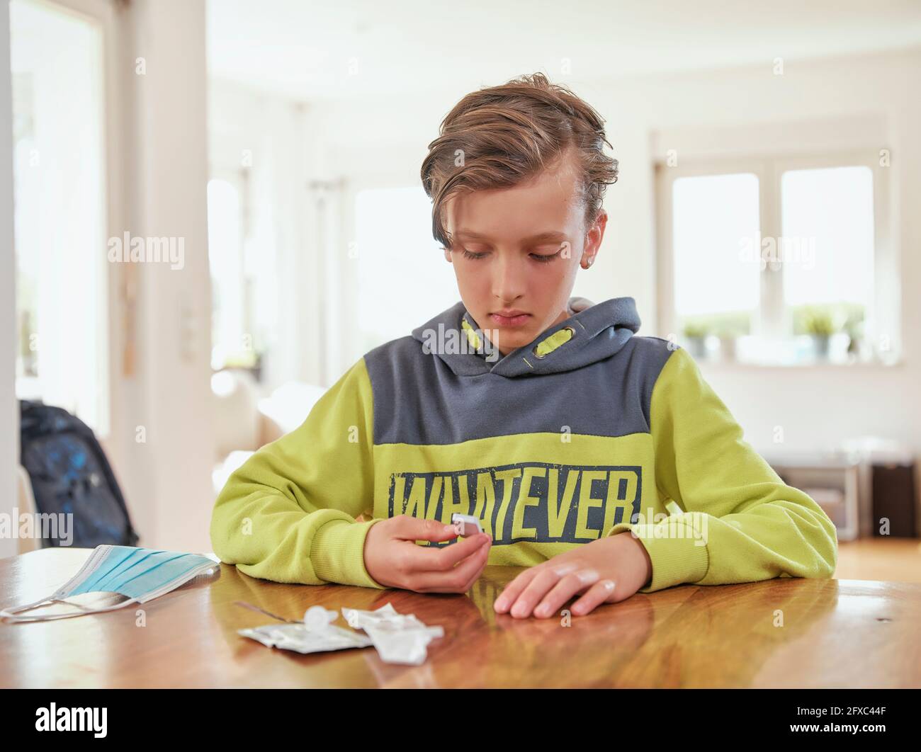 Serious boy analyzing covid-19 test at home Stock Photo