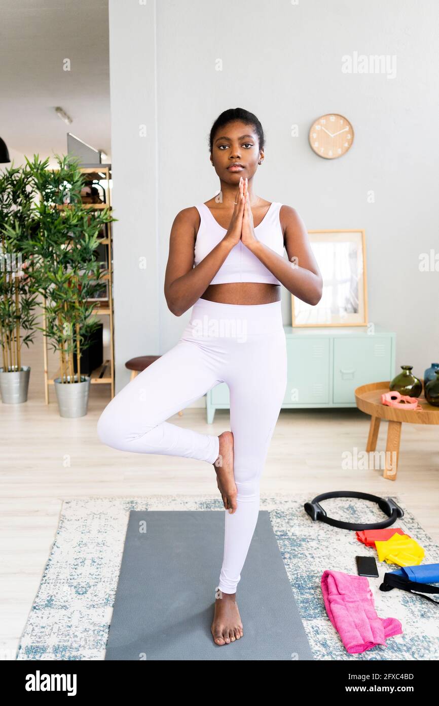Young woman practicing tree pose at home Stock Photo - Alamy