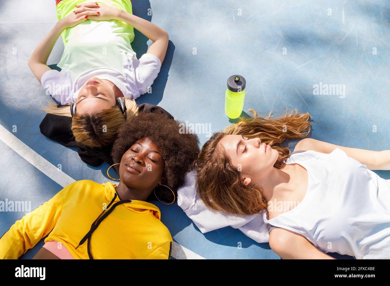 Female friends lying together on sports court floor Stock Photo