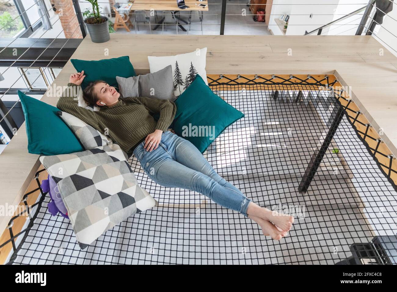 Relaxed young woman lying on hammock in modern home Stock Photo