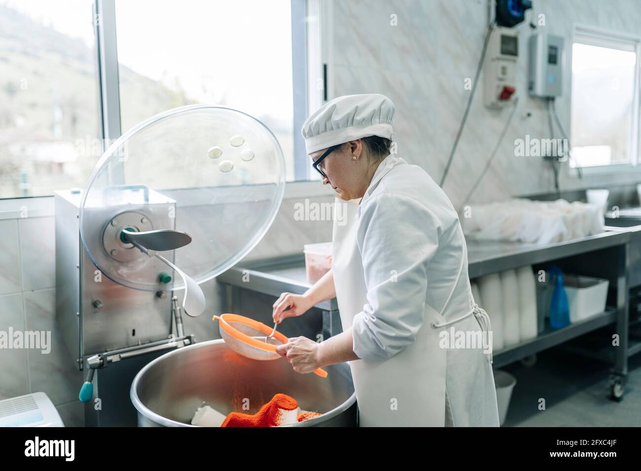 Female cheese expert using strainer in factory Stock Photo